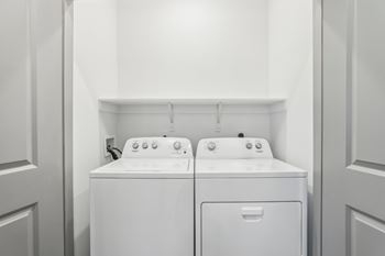 Two white front loading washing machines in a laundry room. at The Junction at Rockledge Apartments, Rockledge, Florida